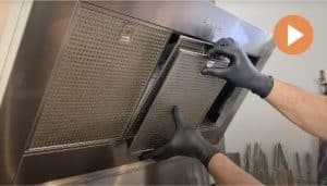 Handskbeklädda händer som plockar av filter från fläkt